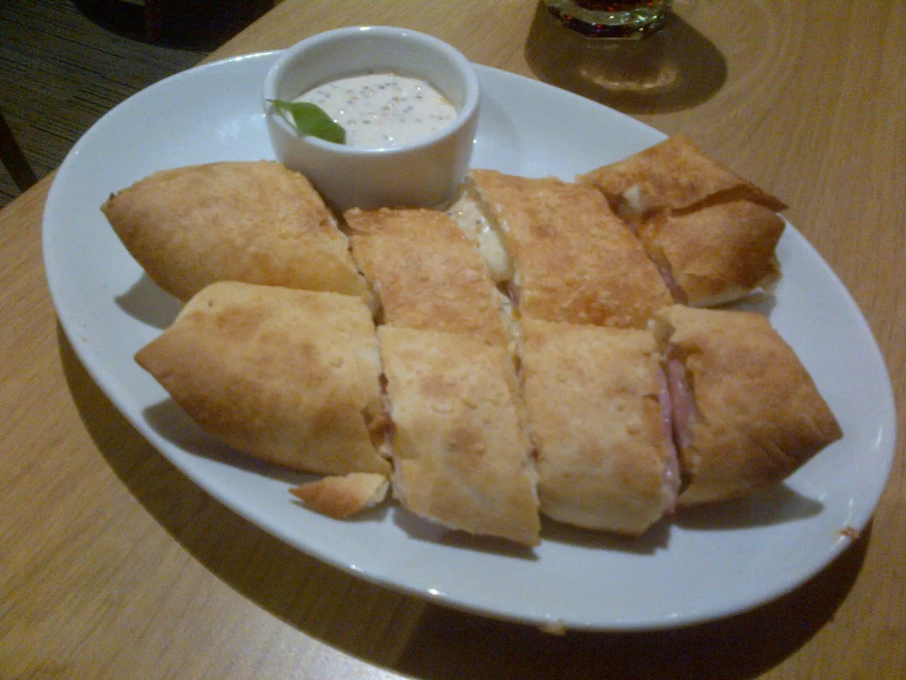 Pokrojone w plastry, złociste rollsy z serem i szynką, jak z Pizza Hut, podane z sosem.