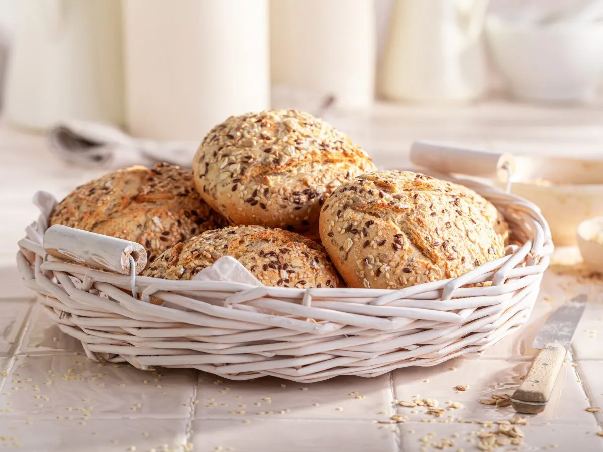 Koszyk pełen bułek z ziarnami. Czy bułki są zdrowe? Te z pewnością tak, dzięki zawartości nasion i płatków owsianych.