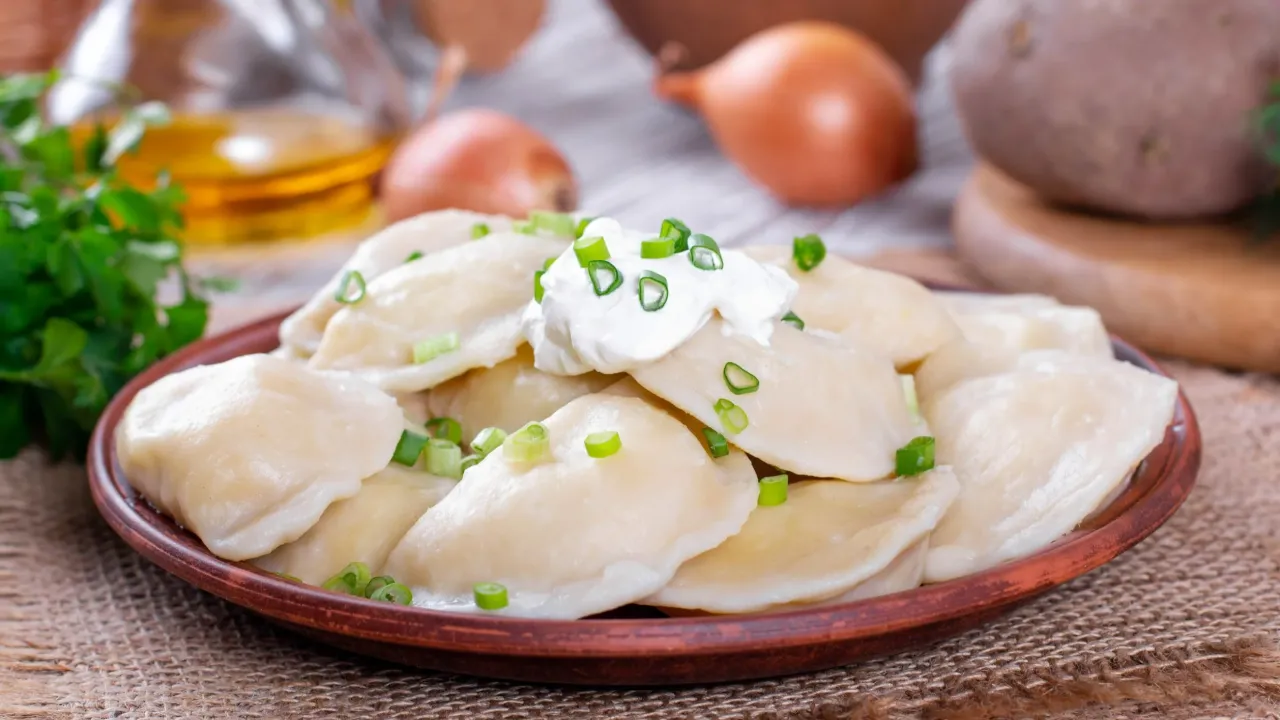 Talerz pysznych, domowych pierogów z okrasą. Zastanawiasz się, ile sztuk pierogów wchodzi na kilogram? To zależy od wielkości, ale na pewno sporo!