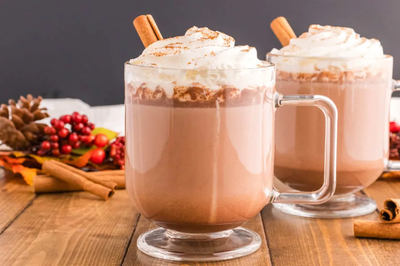 A cup of delicious hot cocoa with steam, cozy setting, cinnamon stick