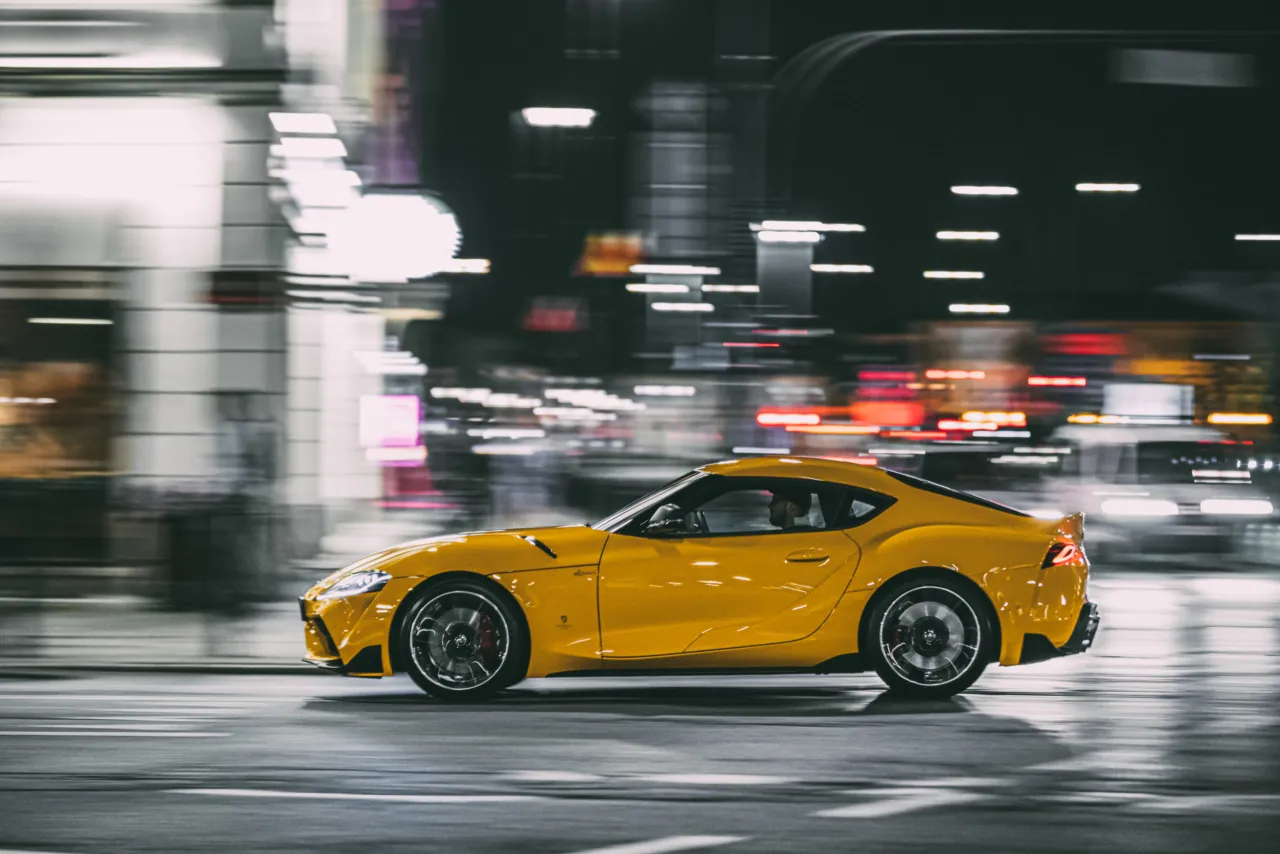 Ż&oacute;łta Toyota Supra pędzi nocą przez miasto, a jej moc (toyota supra ile ma koni) jest odczuwalna w rozmazanych światłach.