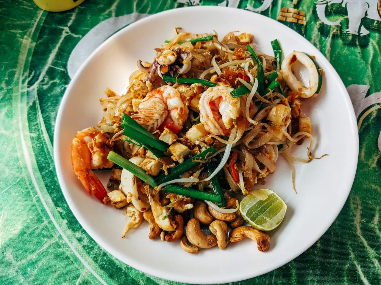 Pad Thai z krewetkami i kalmarami, idealny przykład tajskich przepisów. Podany z orzeszkami ziemnymi i limonką.
