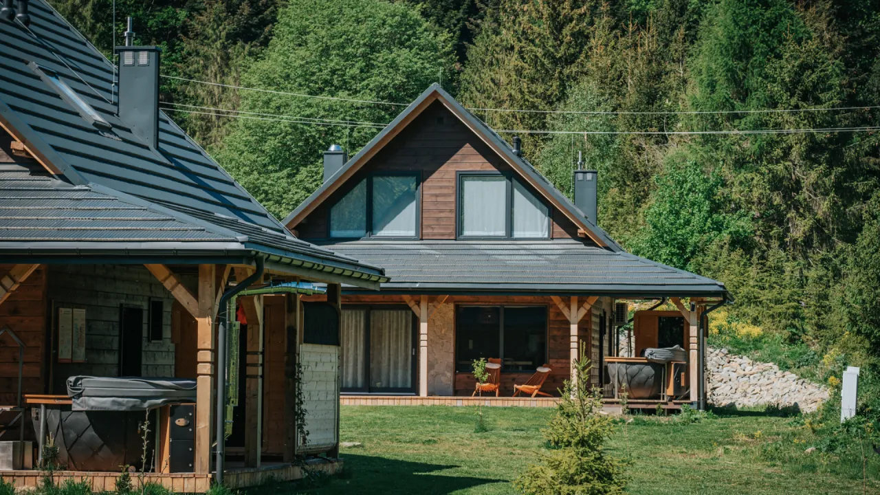 Drewniane domki z bali w Bieszczadach, idealne na noclegi. Widać jacuzzi i piękne otoczenie lasu.