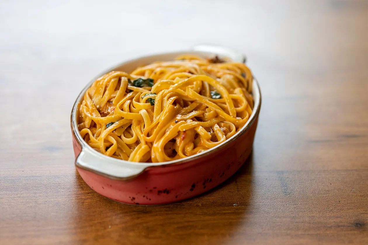 Porcja makaronu w sosie, idealna jako źródło węglowodanów przed czy po treningu.