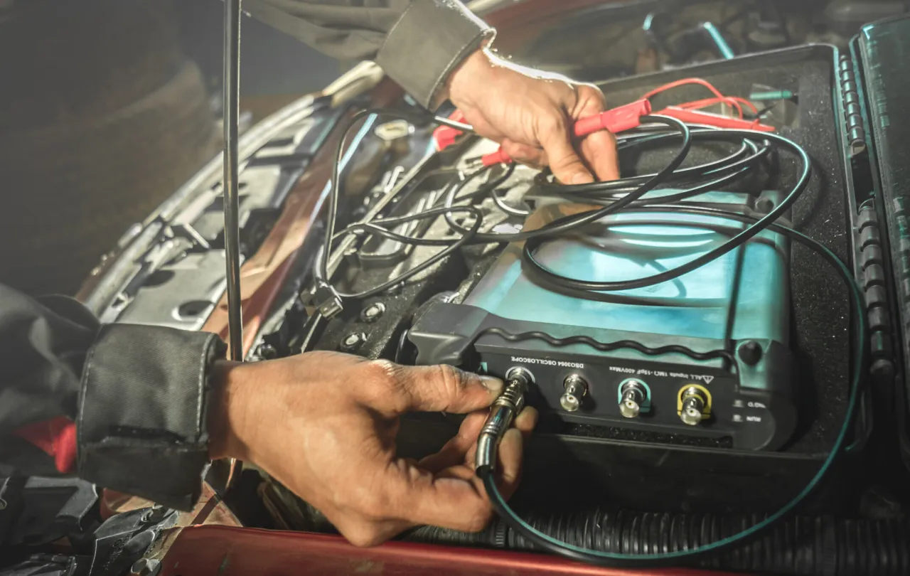 Mechanik podłącza oscyloskop do auta, zastanawiając się, dlaczego mechanicy odmawiają naprawy aut elektrycznych w 2026 roku.