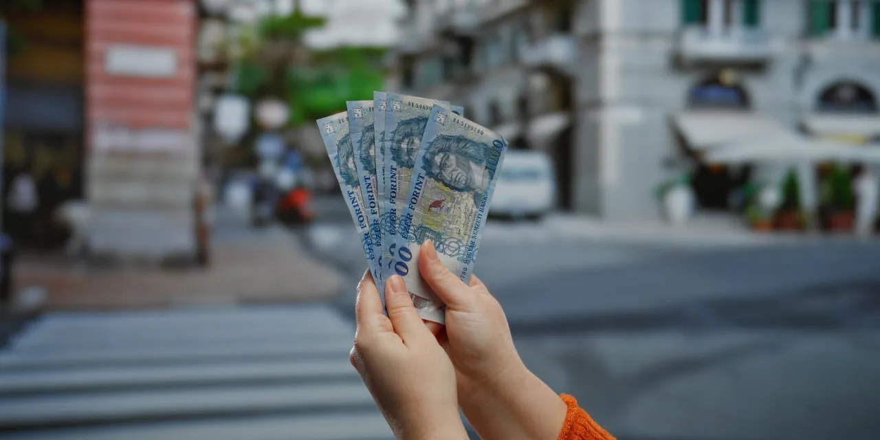 Ręce trzymające banknoty 1000 forint&oacute;w. Zastanawiasz się, ile kosztuje chleb na Węgrzech?