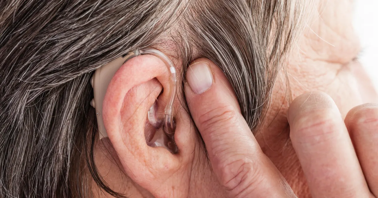 Ucho z aparatem słuchowym na baterie lub akumulator. Dyskretne urządzenie poprawiające słyszenie.