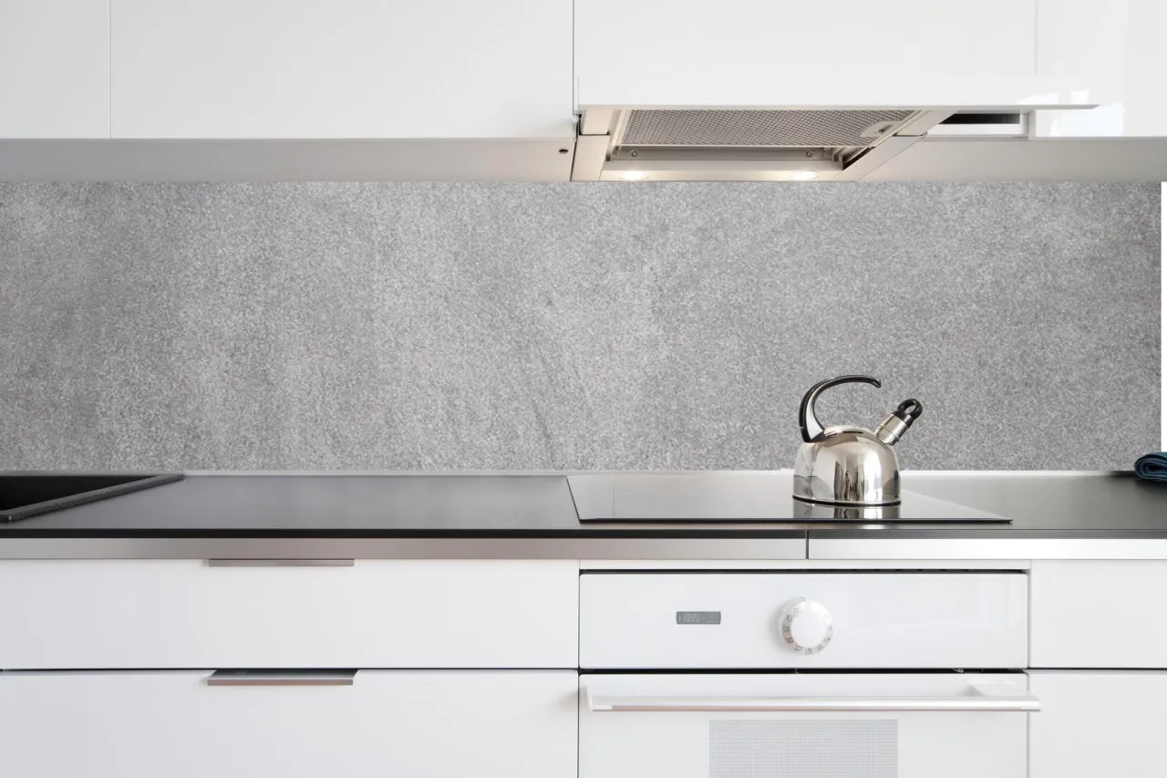 Nowoczesna kuchnia z szarym panelem ściennym imitującym kamień – świetna alternatywa co na ścianę w kuchni zamiast płytek. Czajnik czeka na herbatę.