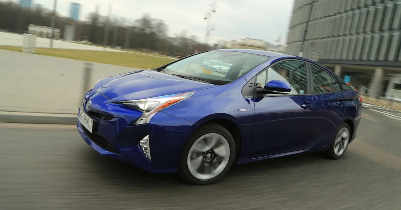 Niebieska Toyota Prius hybryda w ruchu miejskim. Zastanawiasz się, ile pali Toyota Prius hybryda? Ten model jest znany z niskiego spalania.