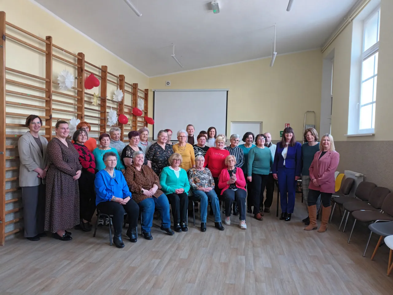 Grupa uśmiechniętych seniorek pozuje do zdjęcia. To inspiracja, jak założyć klub seniora i spędzać aktywnie czas.