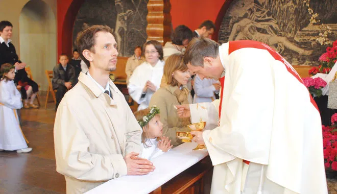 Młodsze dziecko przyjmujące komunię