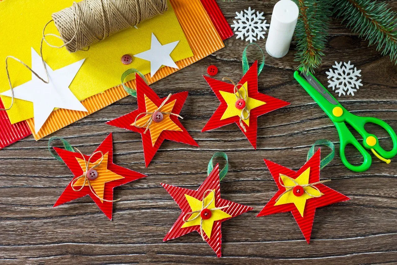 Jak zrobić gwiazdę na choinkę? Kolorowe gwiazdki z papieru, sznurka i guzik&oacute;w, gotowe do zawieszenia.