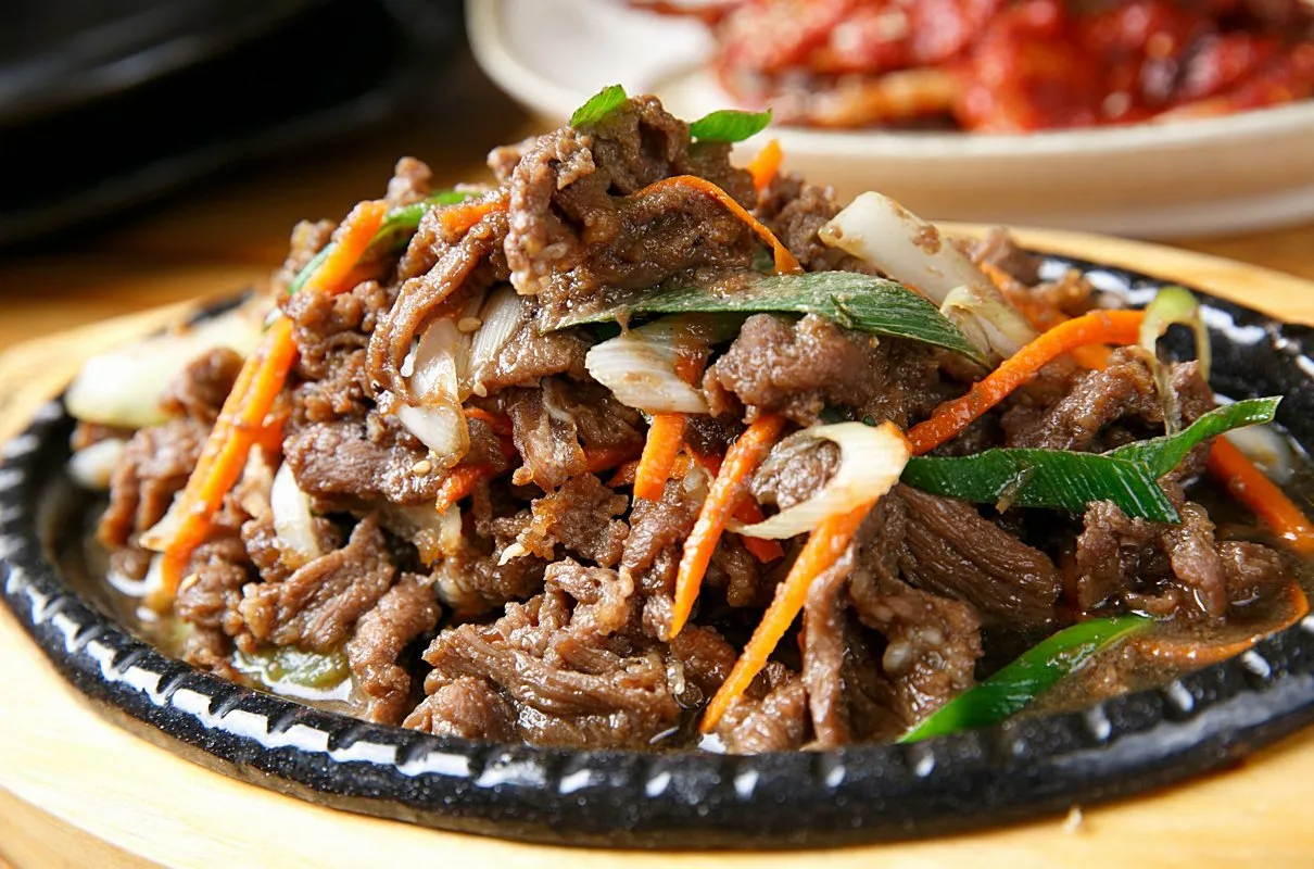 Pyszne bulgogi przepis na gorącej patelni z wołowiną, marchewką i dymką.