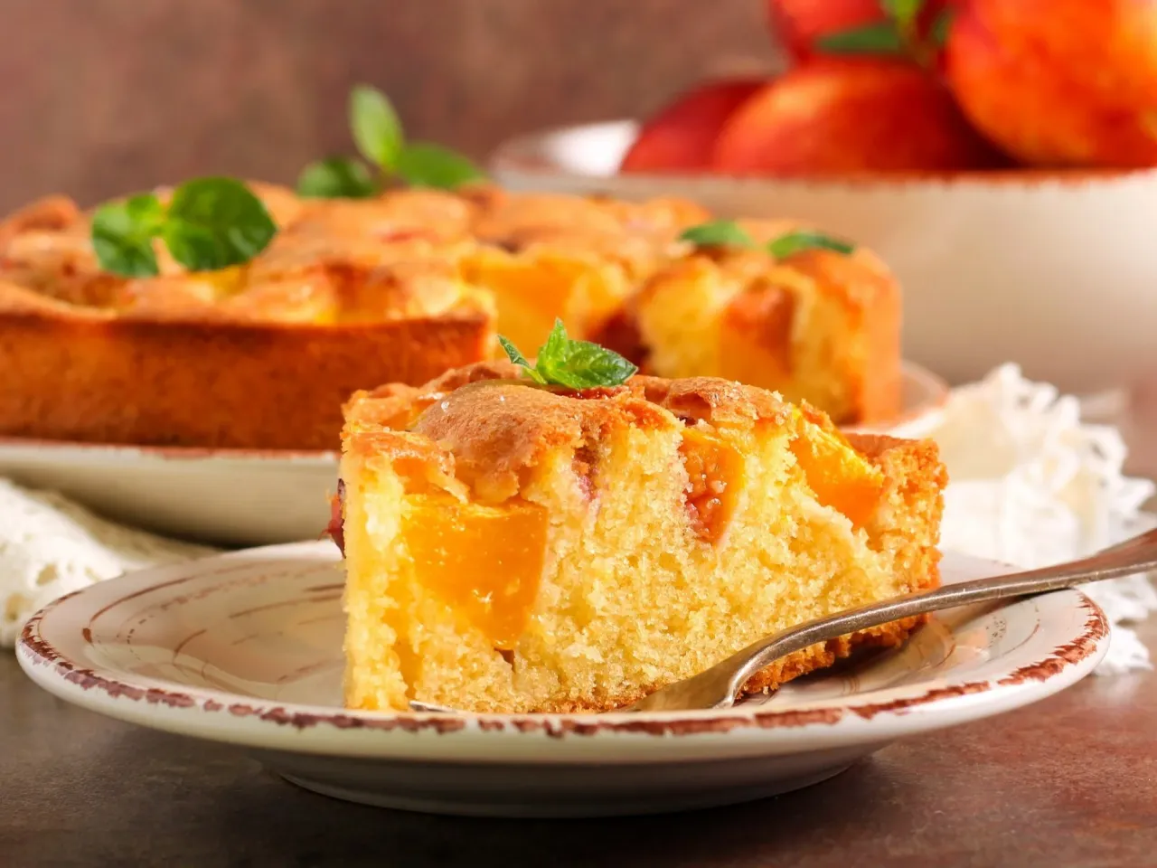 Pyszny, wilgotny przepis na ciasto kręcone z brzoskwiniami, udekorowane listkami mięty. Idealne na deser.