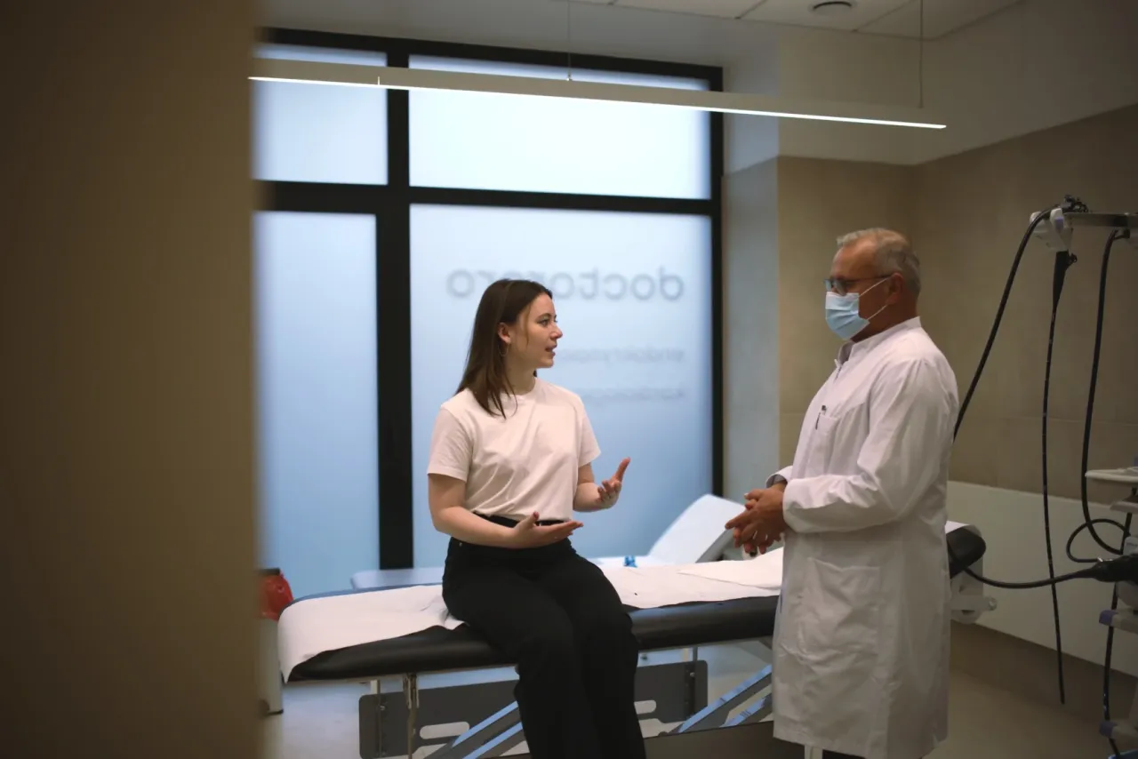 Lekarz proktolog, jaki lekarz leczy hemoroidy, rozmawia z pacjentką w gabinecie.