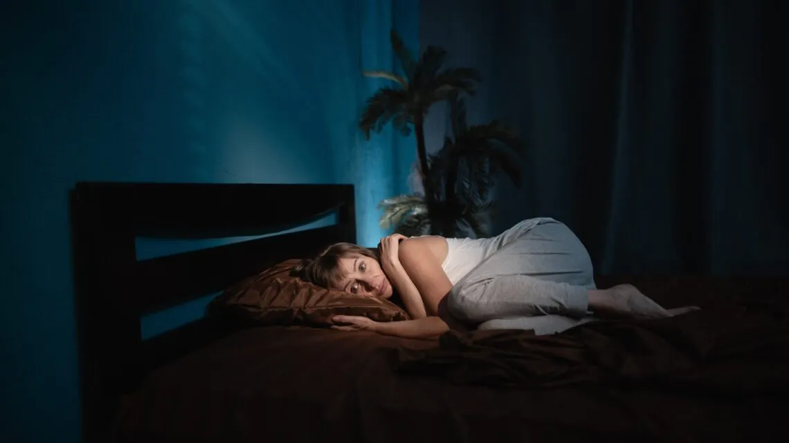osoba dorosła przestraszona w łóżku w nocy