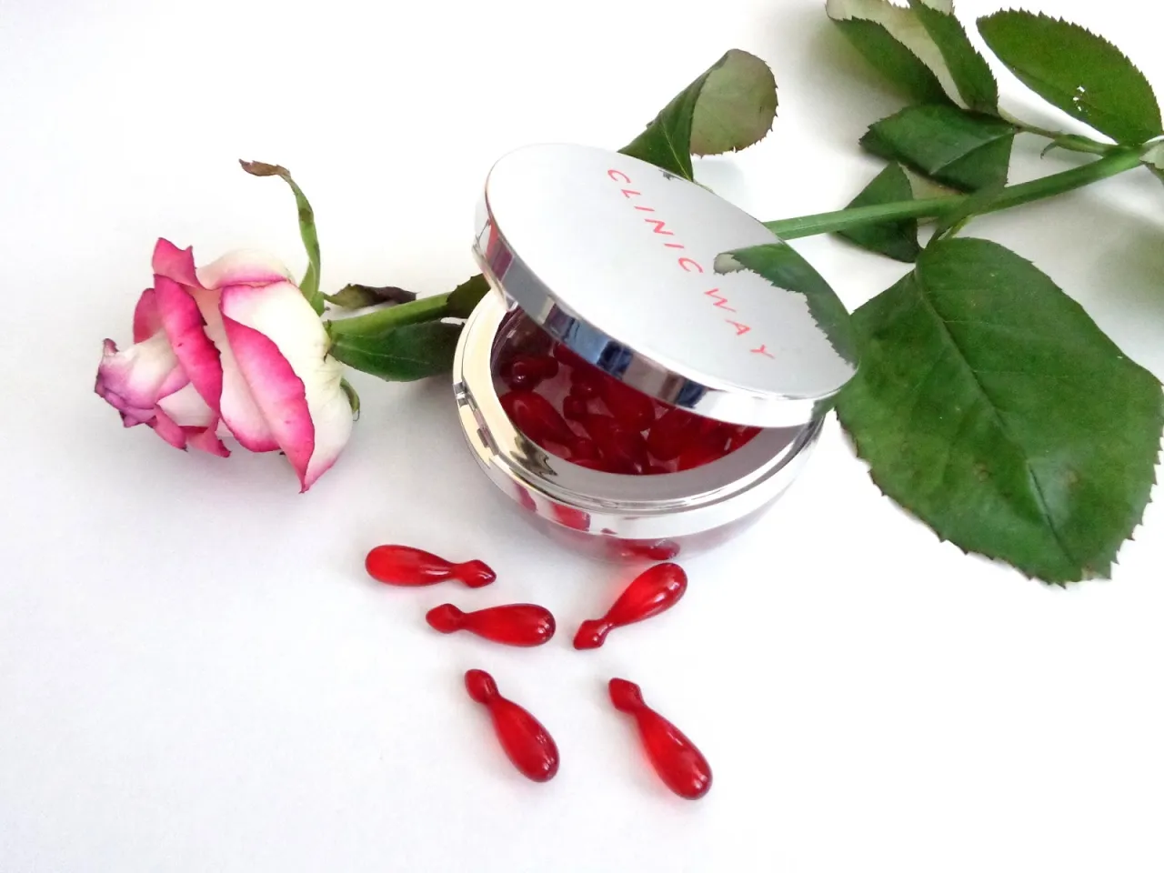 Kapsułki rewitalizujące Clinic Way Dr Ireny Eris obok r&oacute;ży.