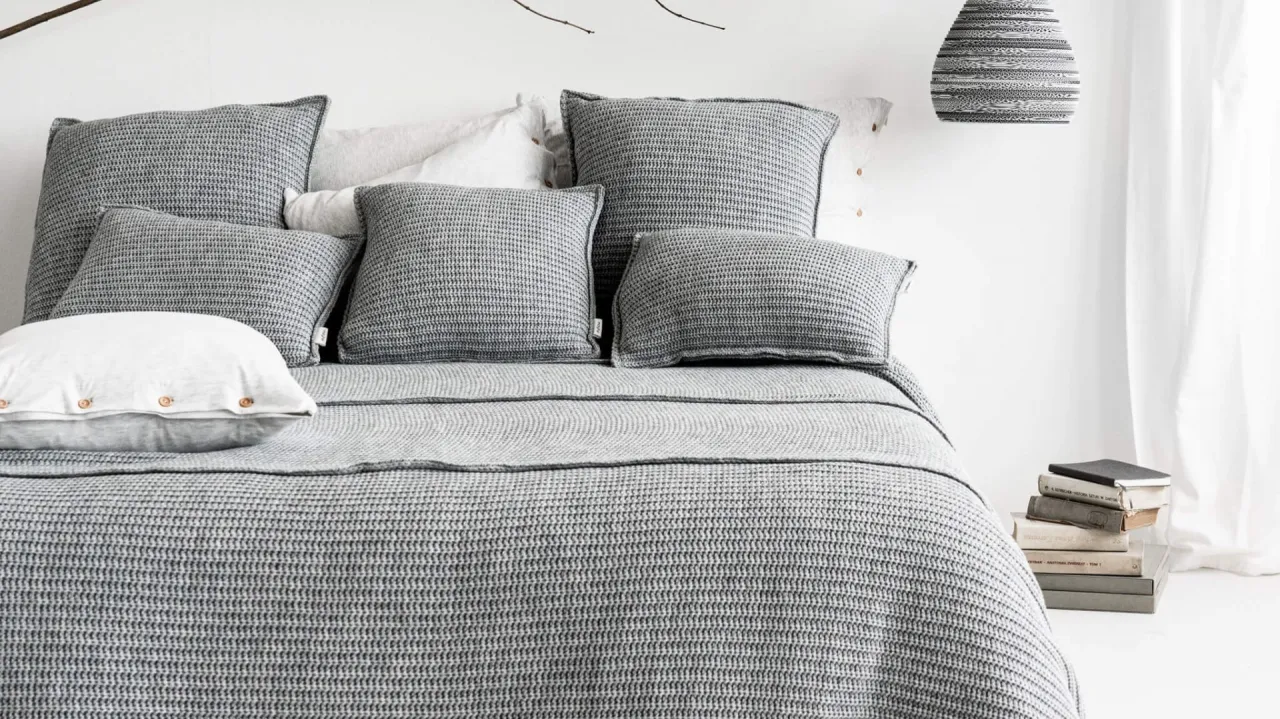 szara sypialnia różne tekstury poduszki pledy