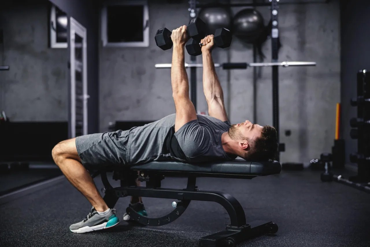 Osoba wykonująca ćwiczenia wielostawowe na siłowni