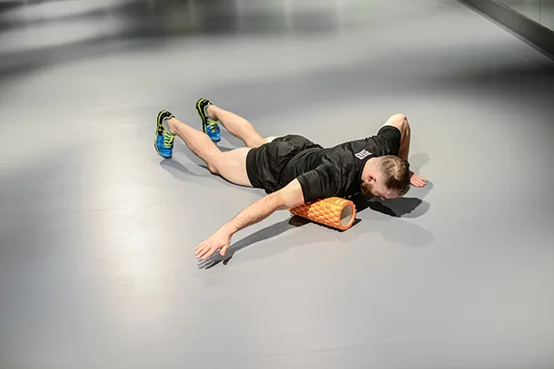 osoba używająca foam rollera do rozciągania klatki piersiowej