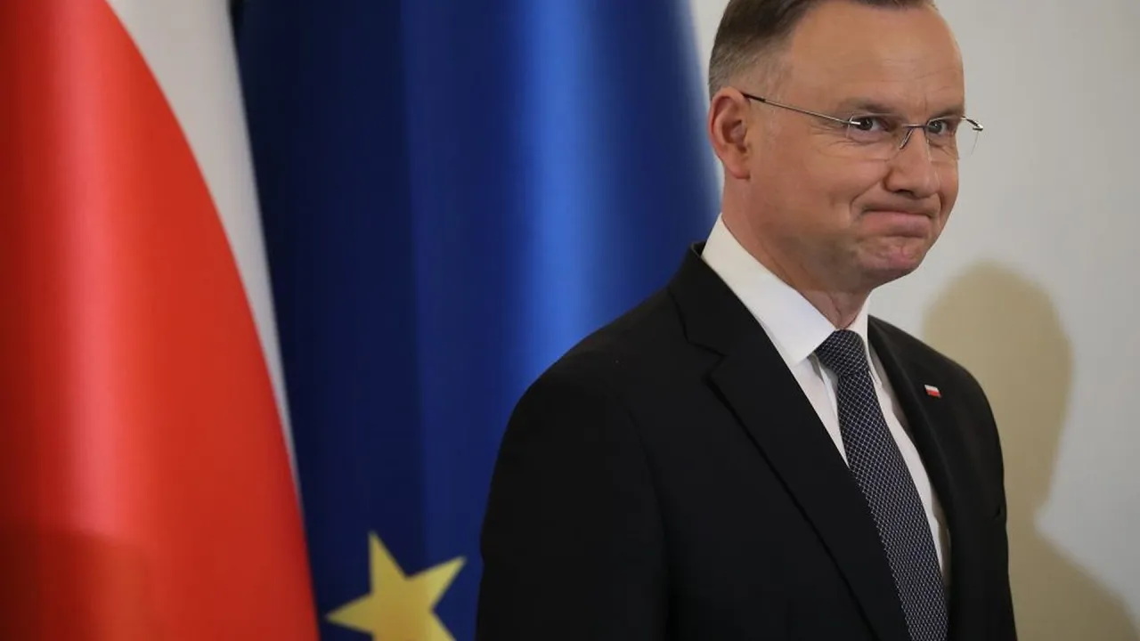 Andrzej Duda zamyślony, w garniturze, na tle flagi Polski i UE. Czy to prawdziwe powody dla których Andrzej Duda zapowiedział serię wet do ustaw budżetowych?