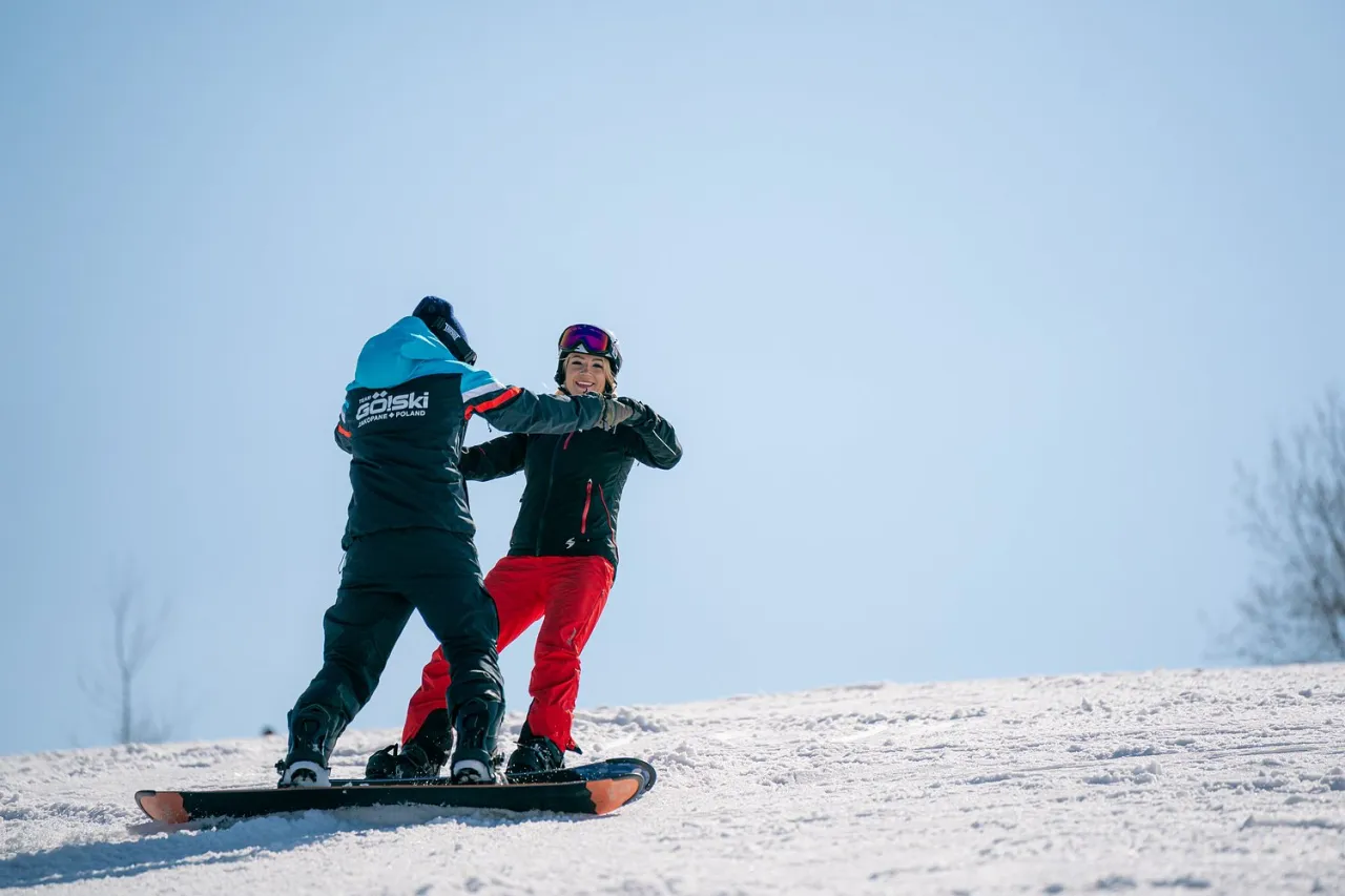 Dwie osoby na snowboardzie cieszą się zimową przygodą. To właśnie snowboard pozwala na takie emocje!