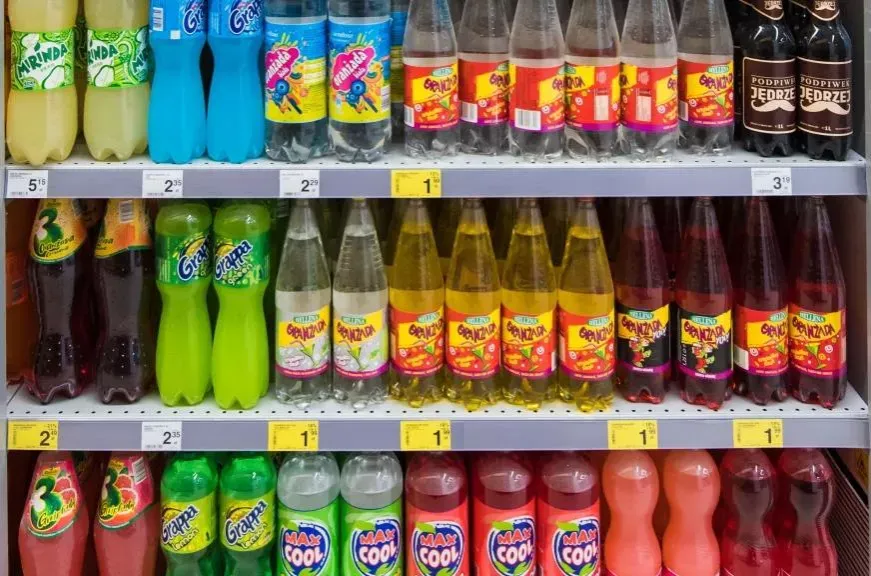Słodzone napoje gazowane i soki owocowe na półce sklepowej