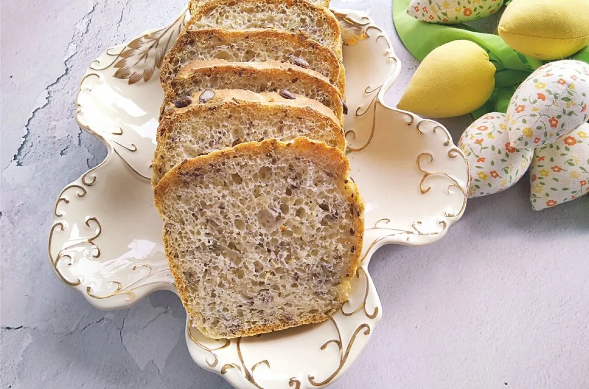 Pokrojony domowy chleb pełnoziarnisty z ziarnami na ozdobnej paterze. Idealny przykład, jak upiec chleb w domu.
