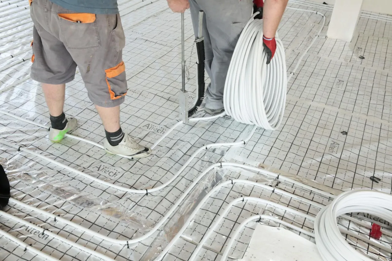 Instalatorzy układają rury do ogrzewania podłogowego. Dowiedz się, ile kosztuje ogrzewanie podłogowe i jakie są jego zalety.
