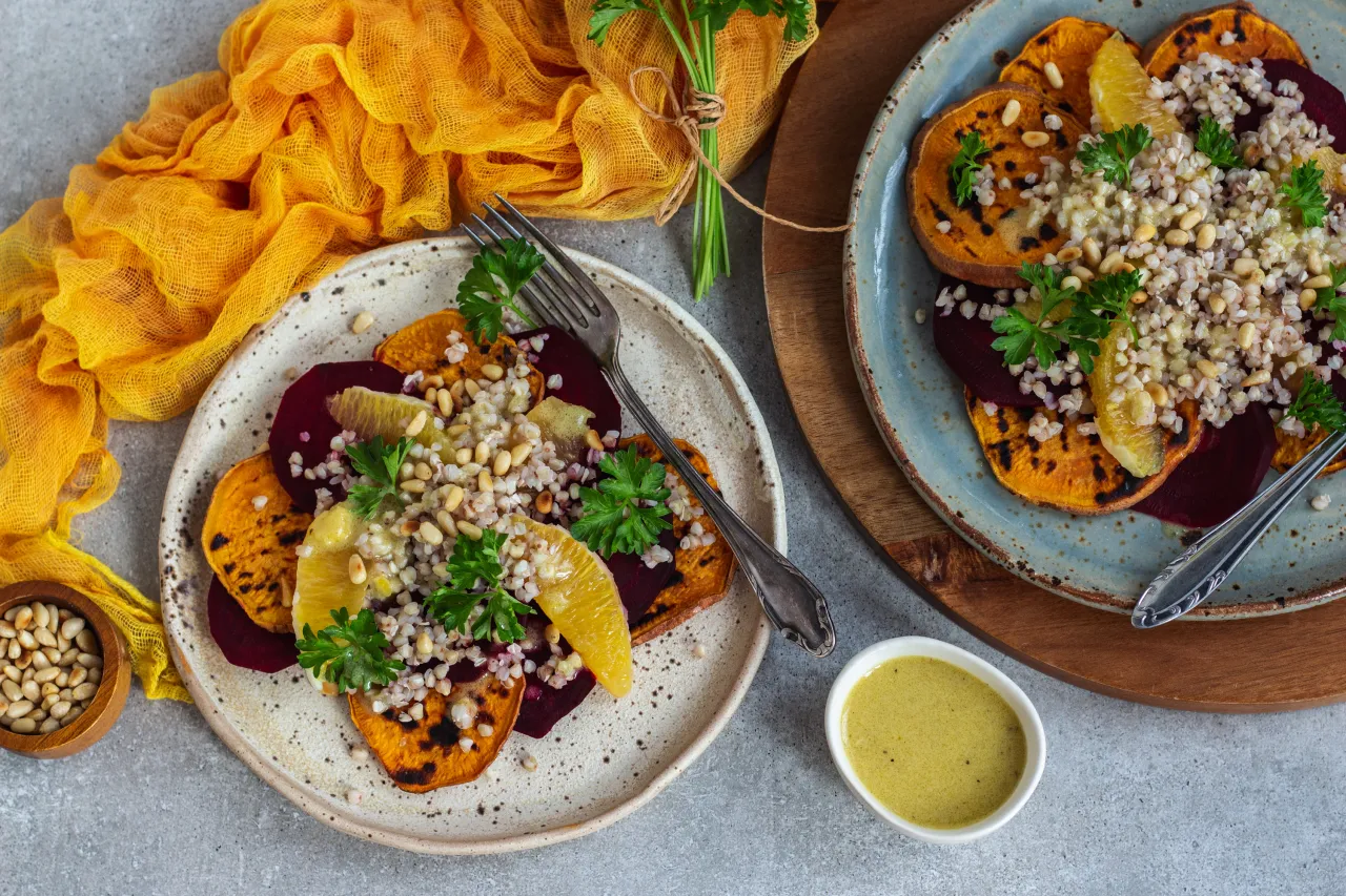 Kolorowa sałatka wegetariańska na imprezę: pieczone bataty, buraki, kasza gryczana, orzeszki piniowe i pomarańcza.