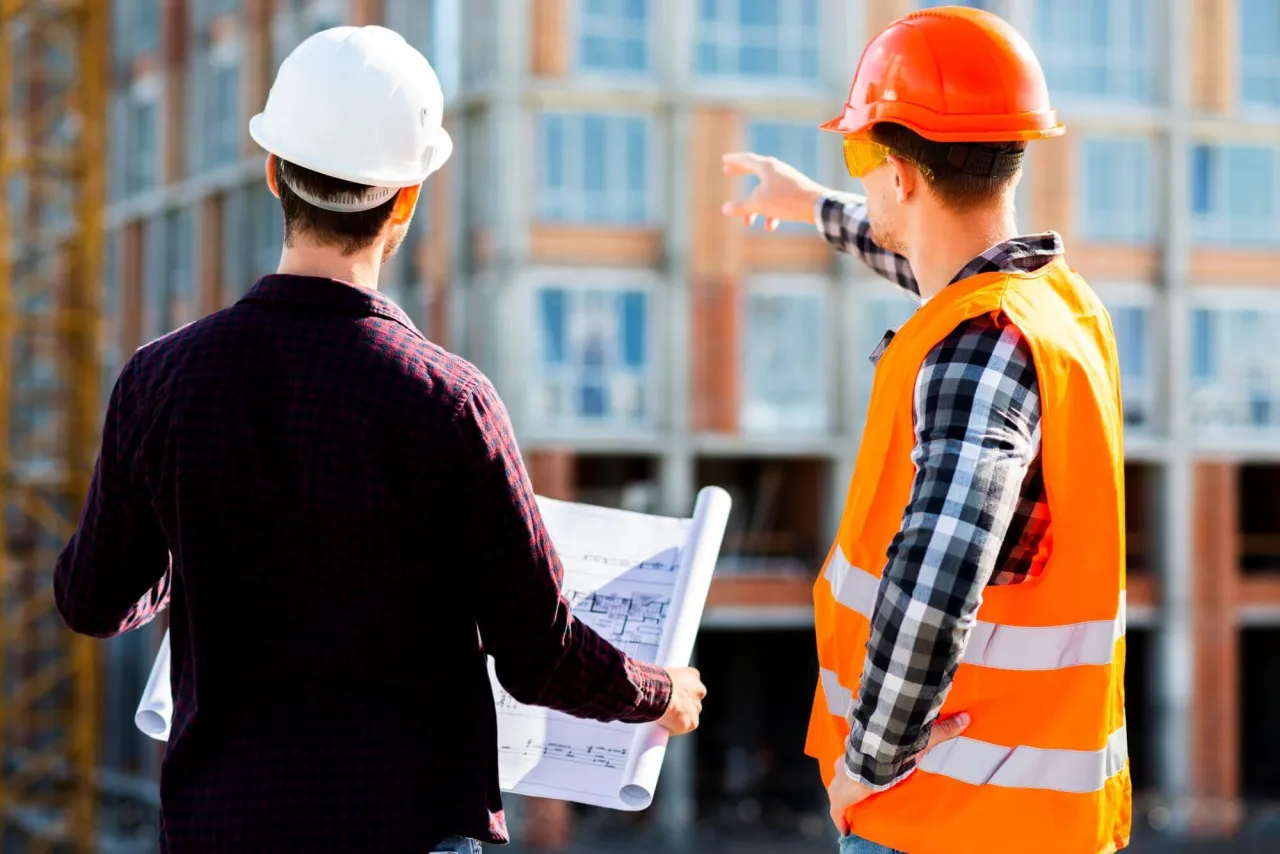 Dwóch budowlańców analizuje plany. Co dalej, gdy wygasło pozwolenie na budowę?