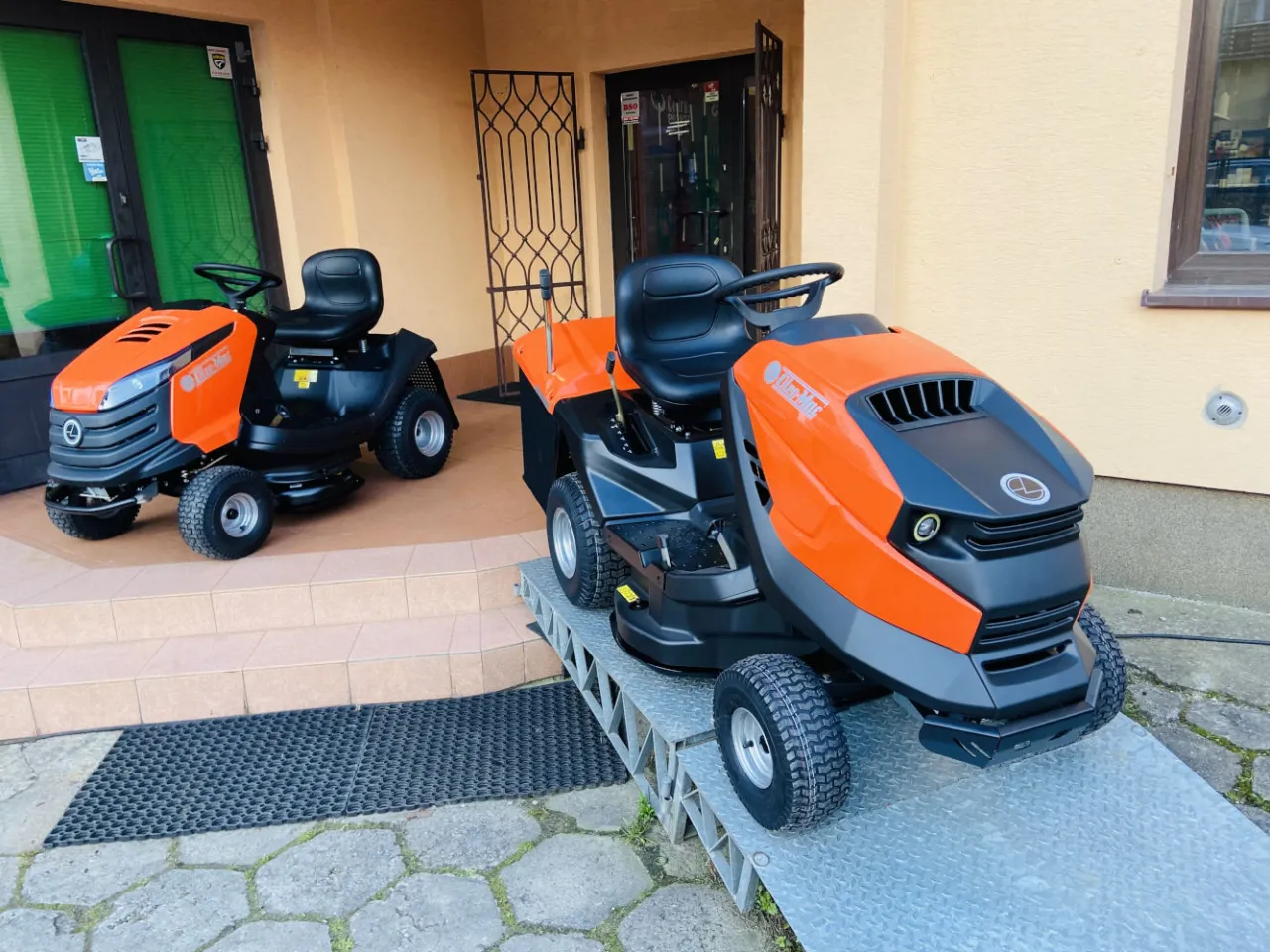 Dwa pomarańczowo-czarne traktorki ogrodowe gotowe do naprawy. Idealne do pielęgnacji trawnika.