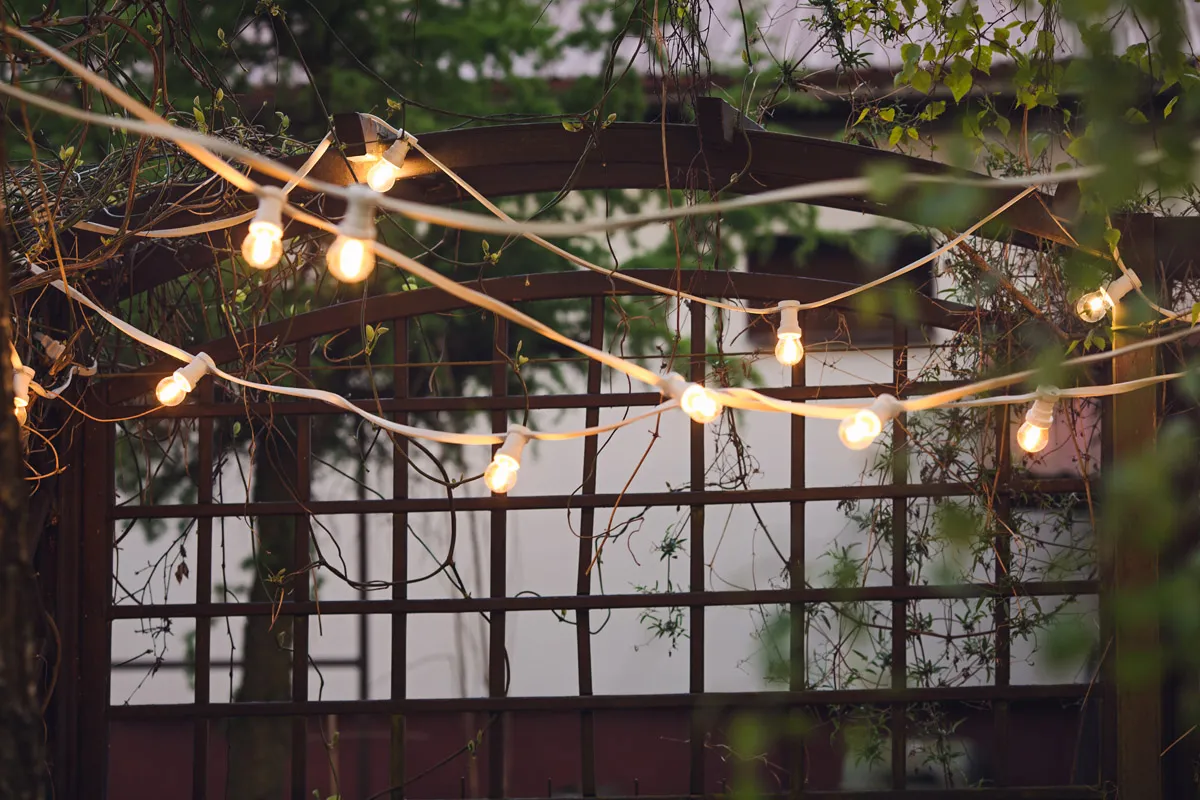 Girlandy żarówek tworzą magiczne oświetlenie na balkonie, idealne na wieczorne spotkania.