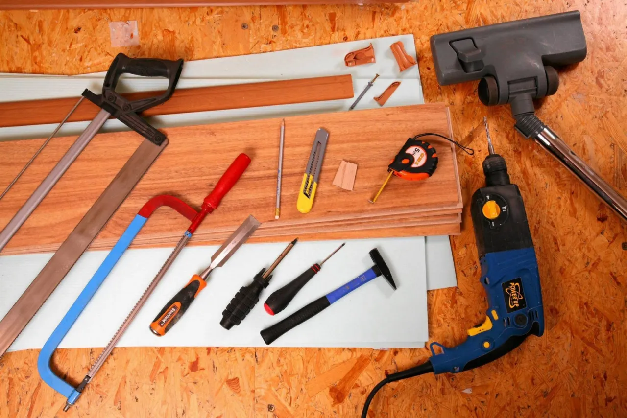 Narzędzia do układania paneli: piła, dłuta, młotek, miarka, nożyk, wiertarka i odkurzacz.