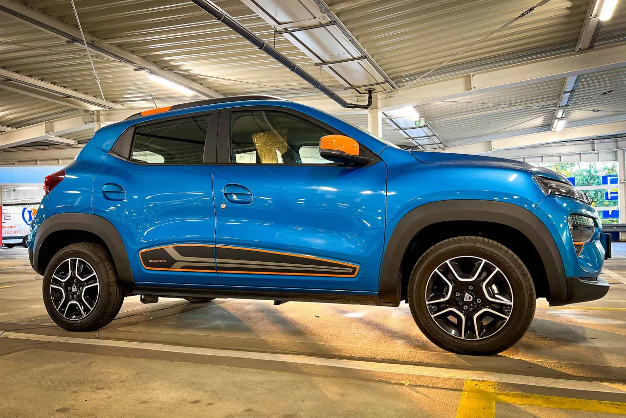 Niebieski samoch&oacute;d elektryczny z pomarańczowymi akcentami. Zastanawiasz się, ile kosztuje najtańszy samoch&oacute;d elektryczny? Ten model może być odpowiedzią.