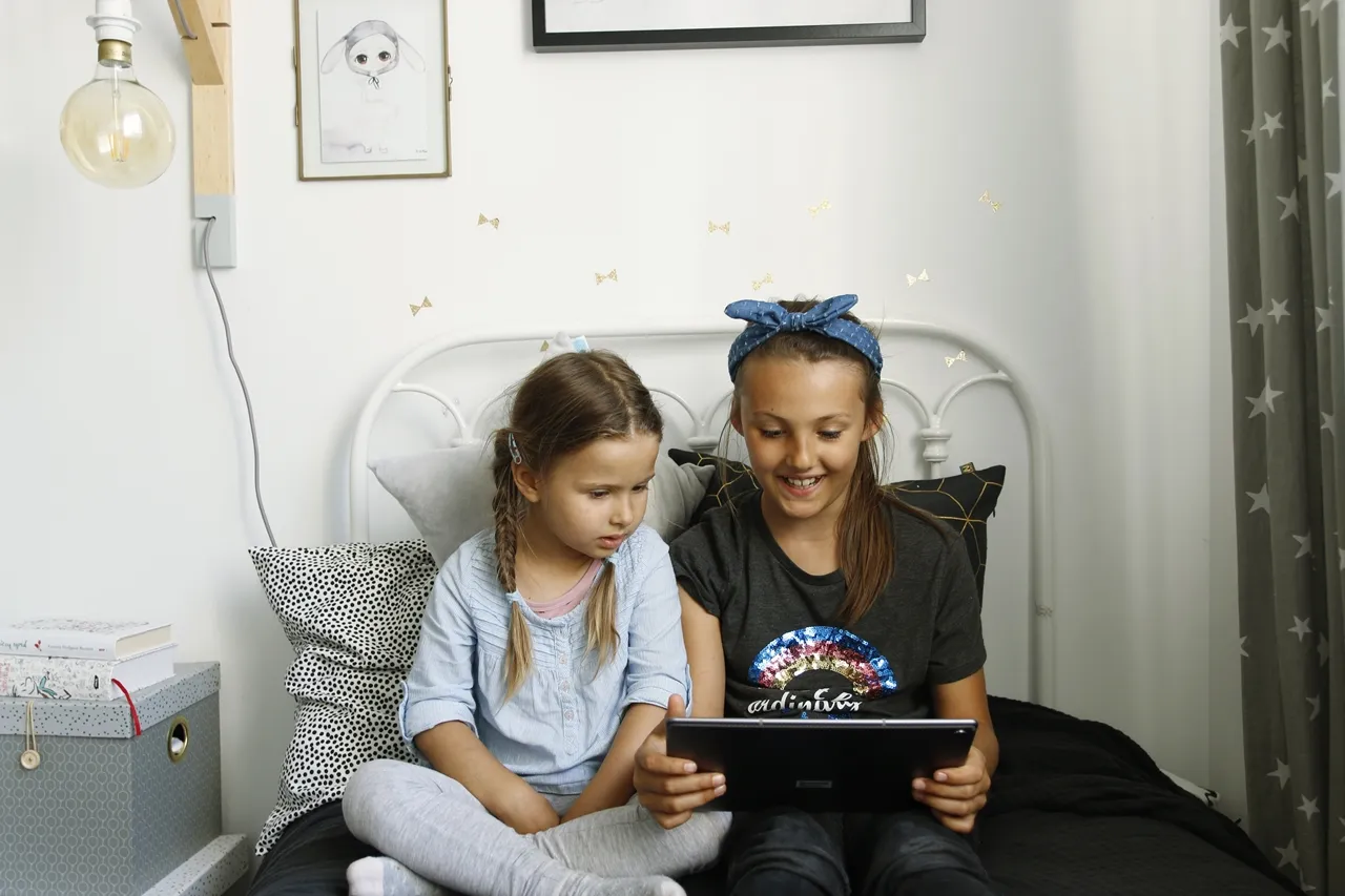 Rodzic i dziecko razem przeglądają finanse na tablecie