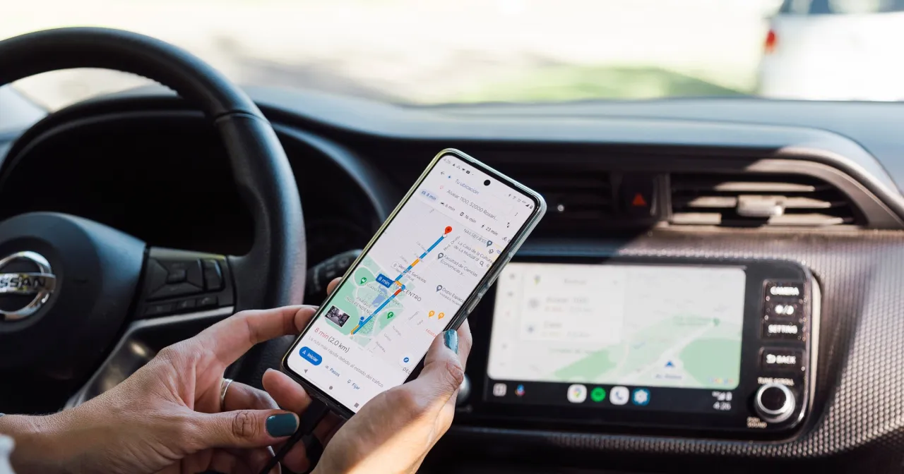 Kierowca sprawdza nawigację na telefonie, by uniknąć mandatu za rozmowę przez telefon podczas jazdy.