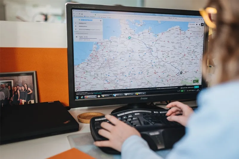 Spedytor przy biurku, telefon, komputer, mapa, organizacja pracy