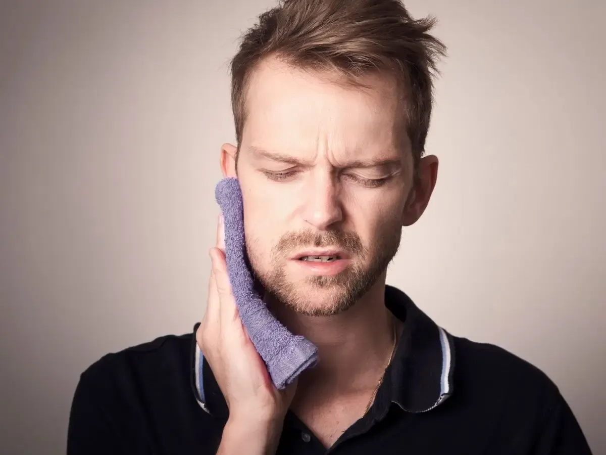 Pacjent po wyrwaniu zęba, rozczarowany, trzymający kieliszek wina