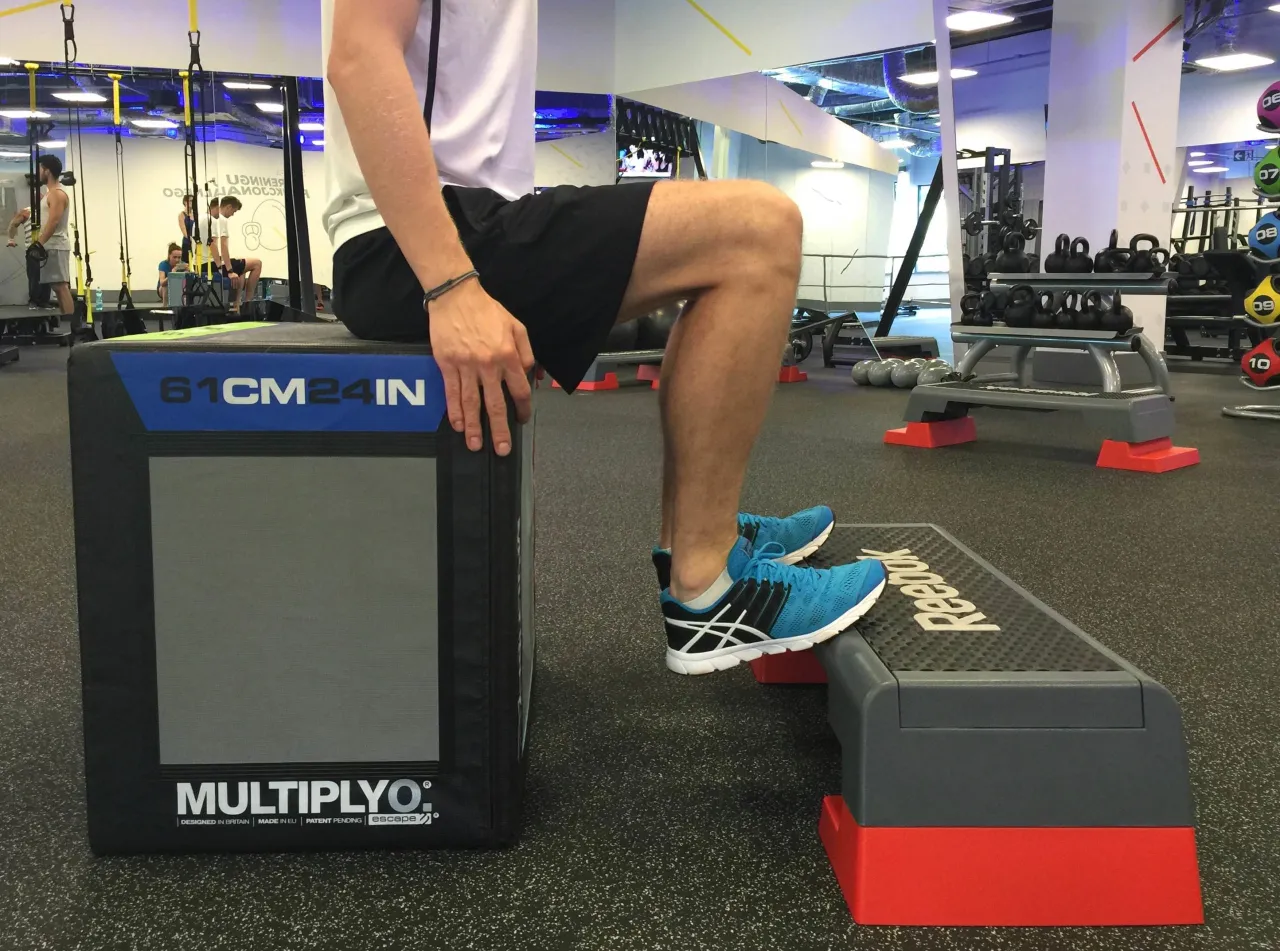 Ćwiczenia po skręceniu kostki: mężczyzna wykonuje ćwiczenie na stepie, sprawdzając stabilność.