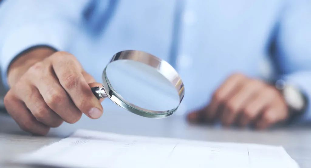 Osoba sprawdzająca dokumenty podatkowe z lupą