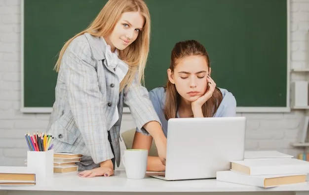 Uczeń z laptopem na tle tablicy w szkole