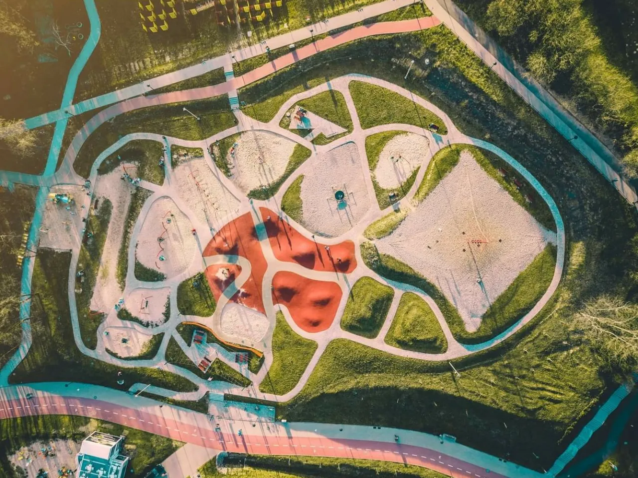 Widok z lotu ptaka na rodzinny park rozrywki Trzy Wzgórza z piaskownicami, placami zabaw i ścieżkami.