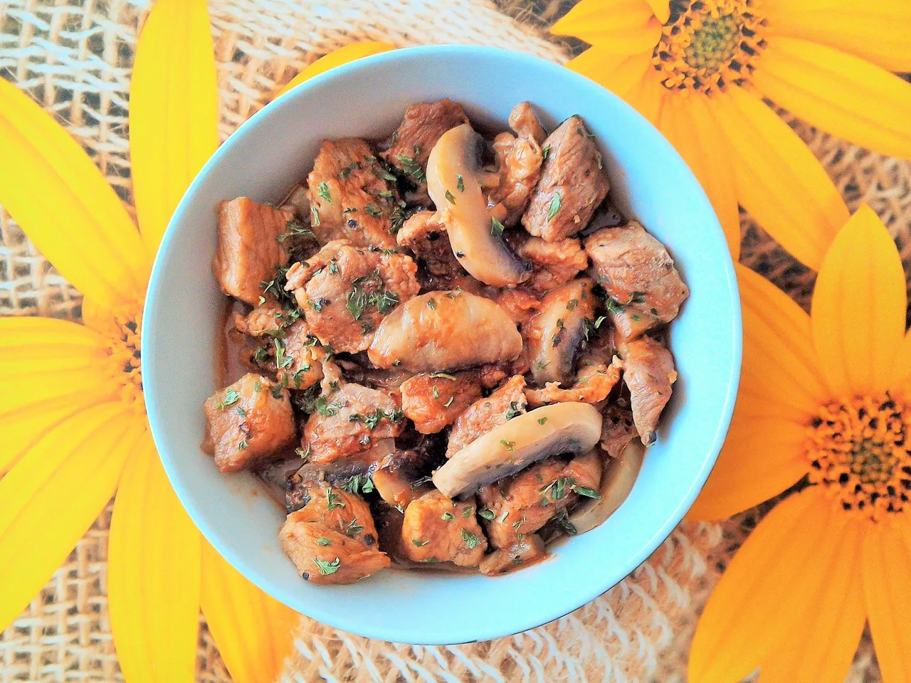 Pyszne danie z biodrówki wieprzowej z pieczarkami, idealne na obiad. Posypane natką pietruszki.