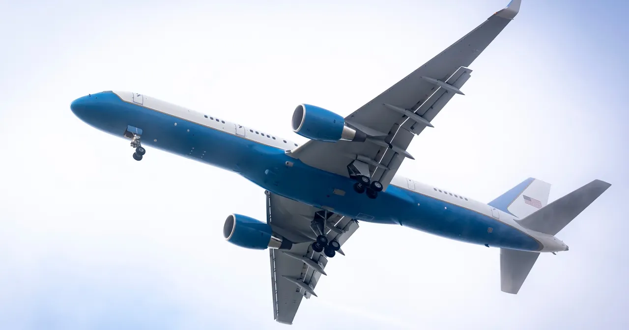 Samolot z niebieskim pasem i amerykańską flagą na ogonie wznosi się na tle nieba. Zastanawiasz się, ile trwa lot do Szwajcarii?