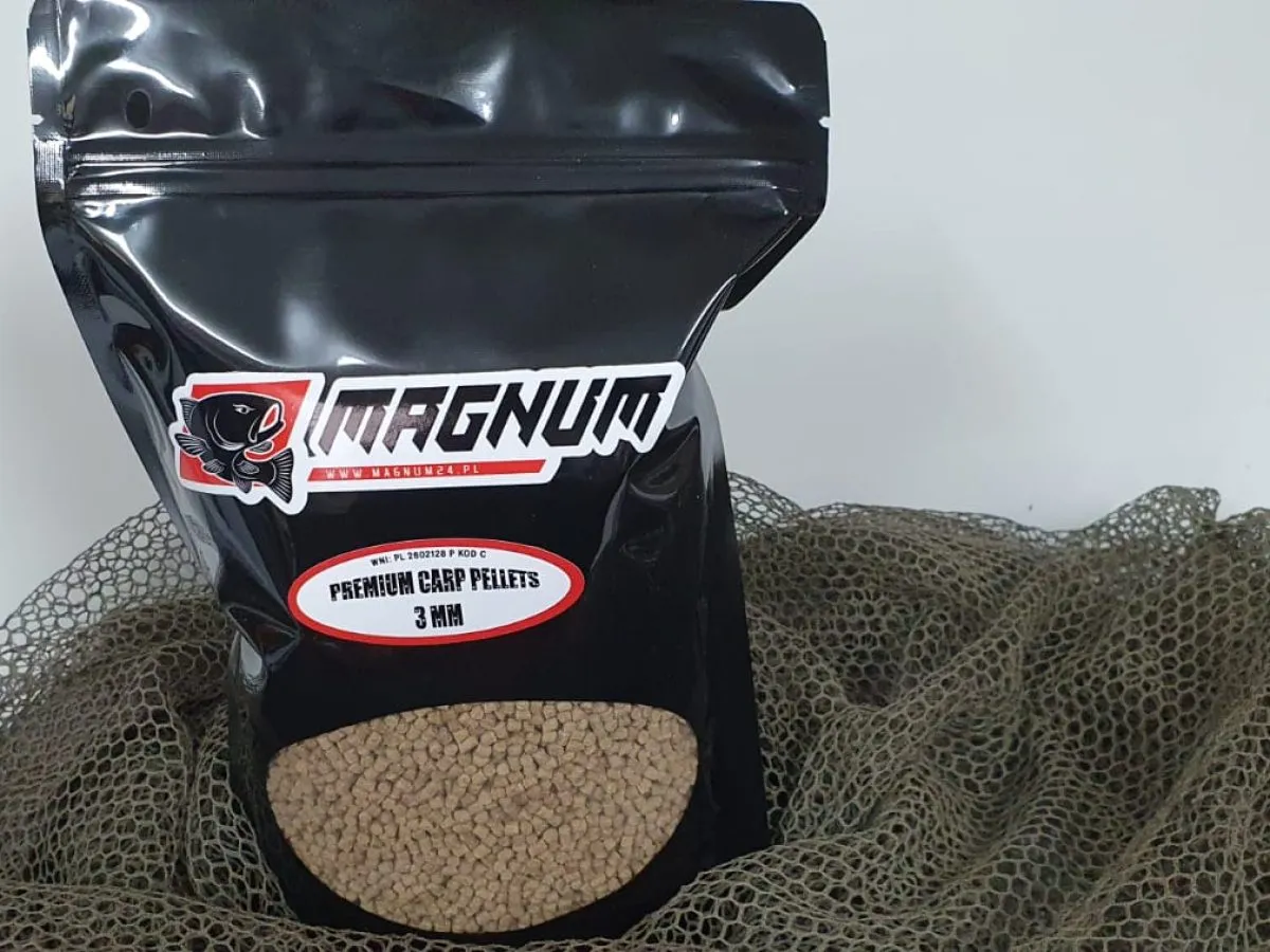 Jaki pellet na haczyk? Opakowanie Magnum Premium Carp Pellets 3mm, idealne na haczyk, leży na siatce wędkarskiej.