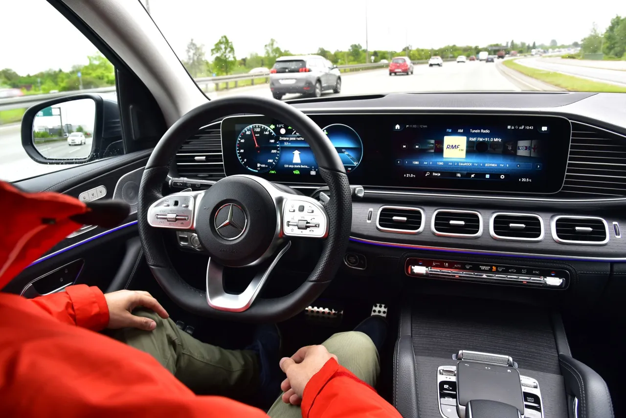 Wnętrze Mercedesa GLE 300 d podczas jazdy autostradą. Widok z perspektywy kierowcy na deskę rozdzielczą i drogę.