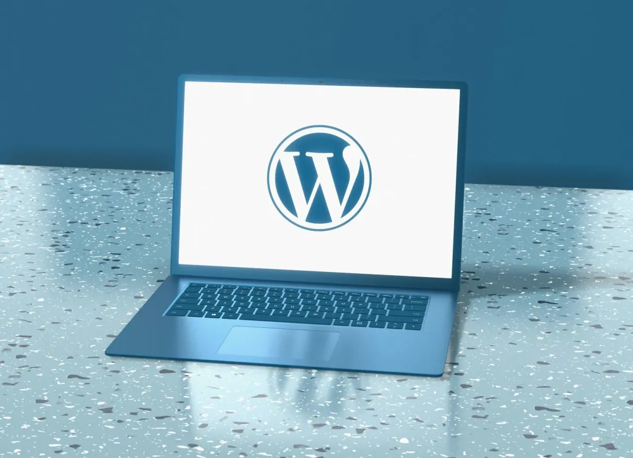 Laptop z logo WordPress na ekranie. To popularne narzędzie do tworzenia stron internetowych.