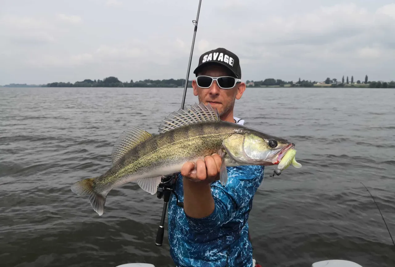 Wędkarz z okazałym sandaczem złowionym na gumę. Idealna jaka wędka na sandacza to taka, kt&oacute;ra pozwoli na precyzyjne podanie przynęty.