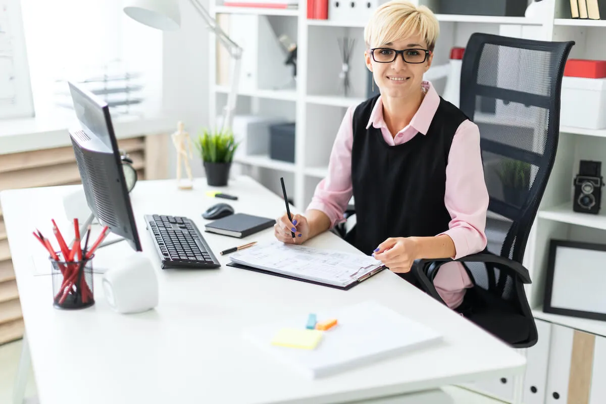 Kobieta w okularach pracuje przy biurku, zastanawiając się, czy po stażu jest obowiązek zatrudnienia.